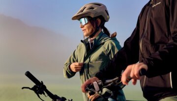 Deux cyclistes avec leurs vélos dans un cadre paisible, équipés de casques et de vêtements techniques.