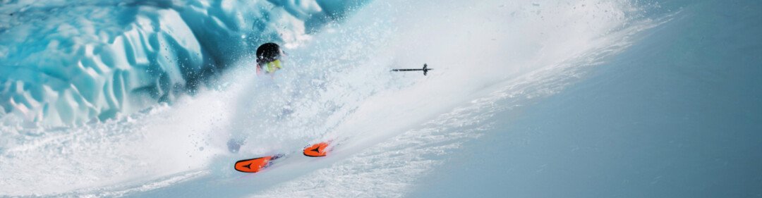 © © Christoph Johann, All Rights Reserved Skiër in diepe poedersneeuw met een gletsjer op de achtergrond. | © © Christoph Johann, All Rights Reserved