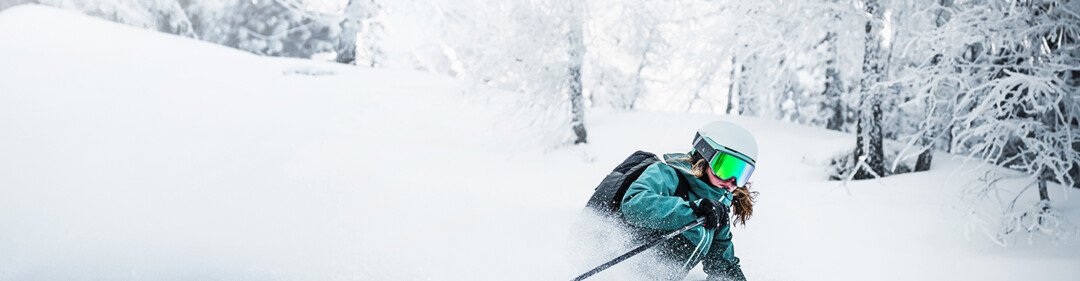 Skieuse traversant la poudreuse dans une forêt enneigée. | © Atomic Austria GmbH