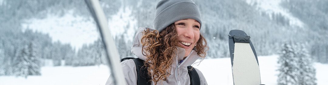 Femme souriante avec des skis dans la neige. | © Atomic Austria GmbH