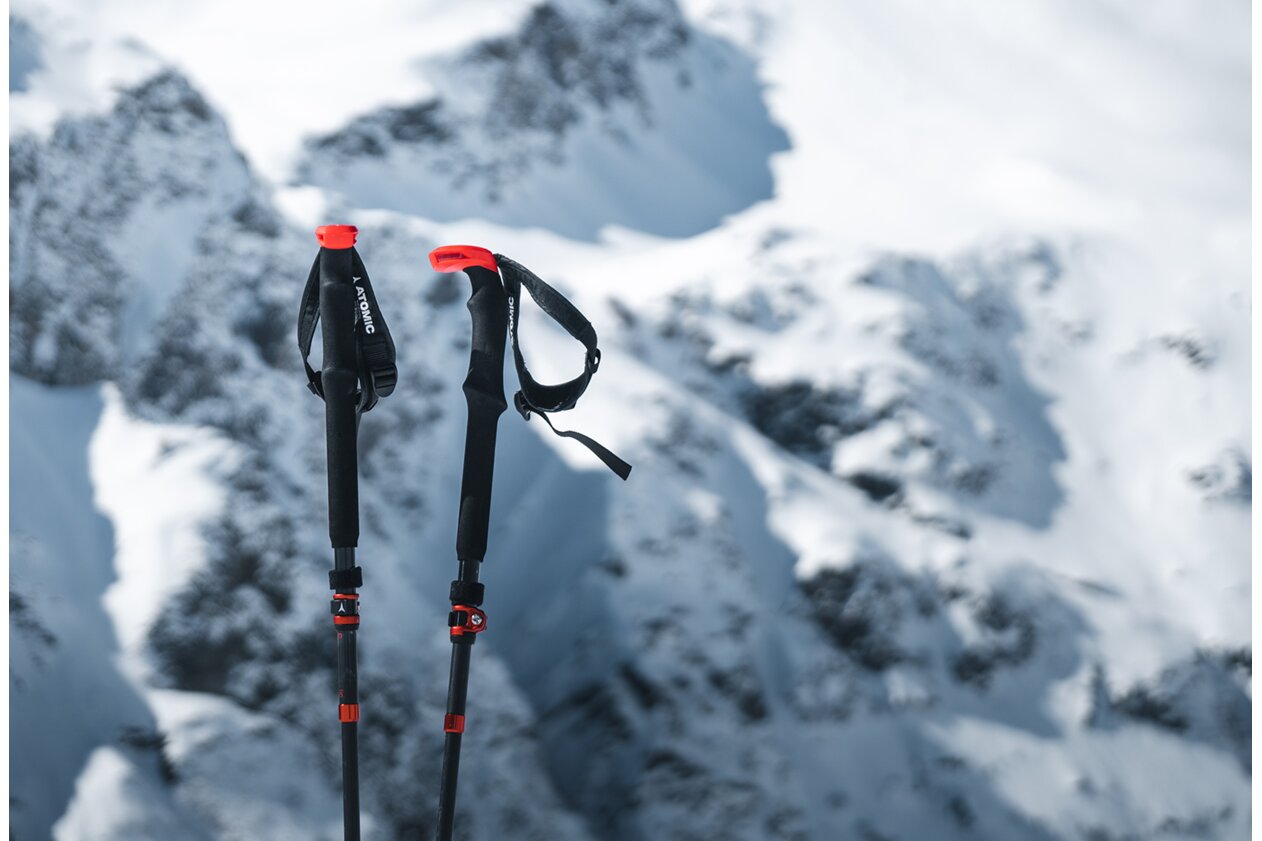 Deux bâtons de ski Atomic dans la neige avec des montagnes enneigées en arrière-plan. | © Atomic Austria GmbH