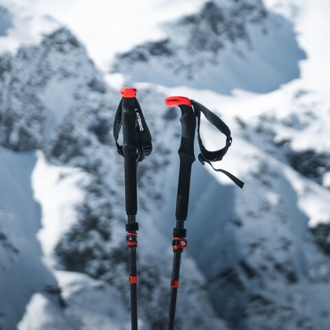 Deux bâtons de ski Atomic dans la neige avec des montagnes enneigées en arrière-plan. | © Atomic Austria GmbH