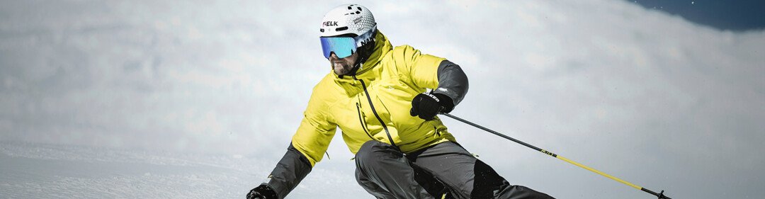 © Fischer Sports GmbH Skiër in gele jas skiet een besneeuwde helling af. | © Fischer Sports GmbH