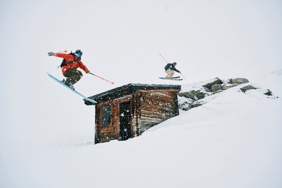 © Fischer Sports GmbH Two skiers jumping over a building in the snow. | © Fischer Sports GmbH