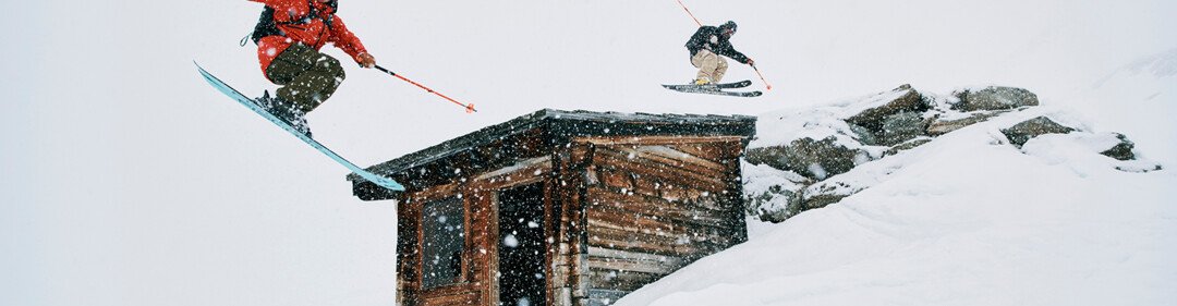 Twee skiërs springen over een gebouw in de sneeuw. | © Fischer Sports GmbH