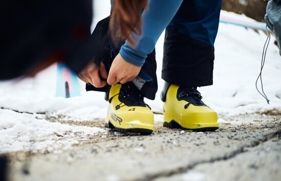 Person lacing up yellow ski boots in snow. | © Fischer Sports GmbH