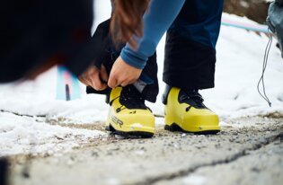 Person lacing up yellow ski boots in snow. | © Fischer Sports GmbH