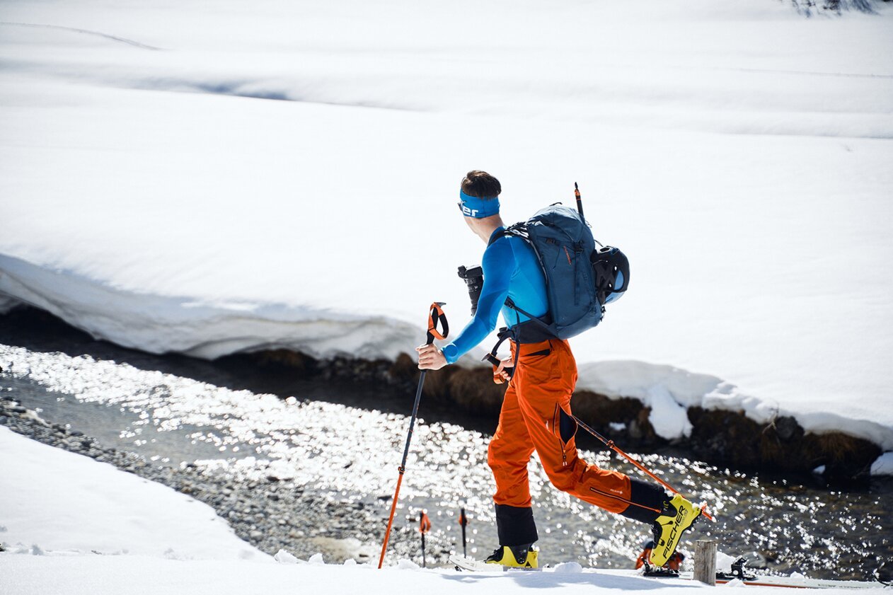 Skieur de randonnée avec sac à dos traversant un paysage enneigé. | © Fischer Sports GmbH