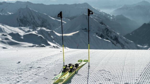 Skis et bâtons dans la neige avec fond de montagne | © Fischer Sports GmbH