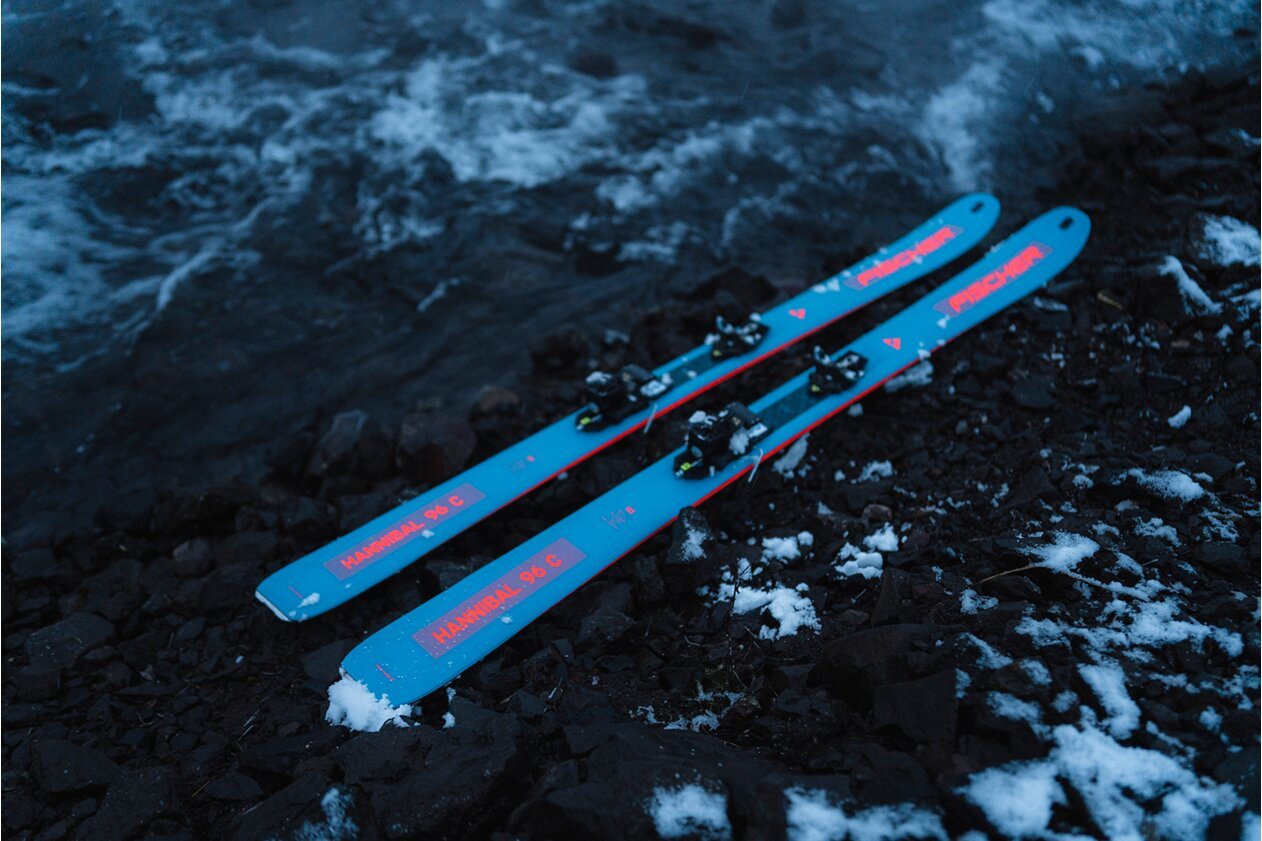 A pair of blue Fischer Hannibal 96 C skis resting on rocky ground with snow. | © Fischer Sports GmbH
