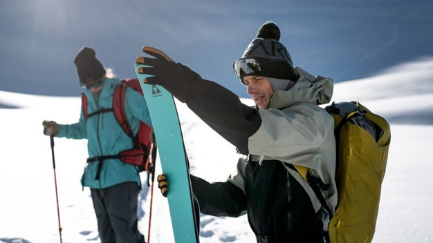 Two ski tourers in the snow, one holding a ski. | © Fischer Sports GmbH