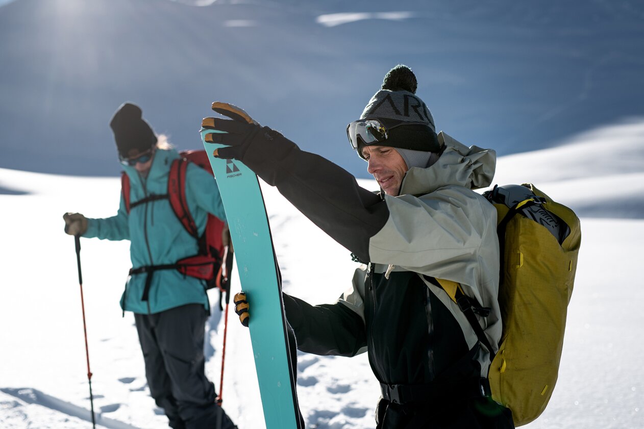 Two ski tourers in the snow, one holding a ski. | © Fischer Sports GmbH