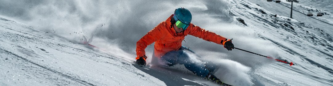 Skieur en veste orange dévalant une pente enneigée. | © Fischer Sports GmbH