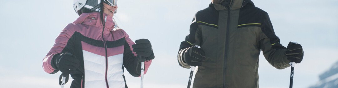 © INTERSPORT International Corporation GmbH Twee skiërs in ski-uitrusting staan te lachen op een besneeuwde dag. | © INTERSPORT International Corporation GmbH