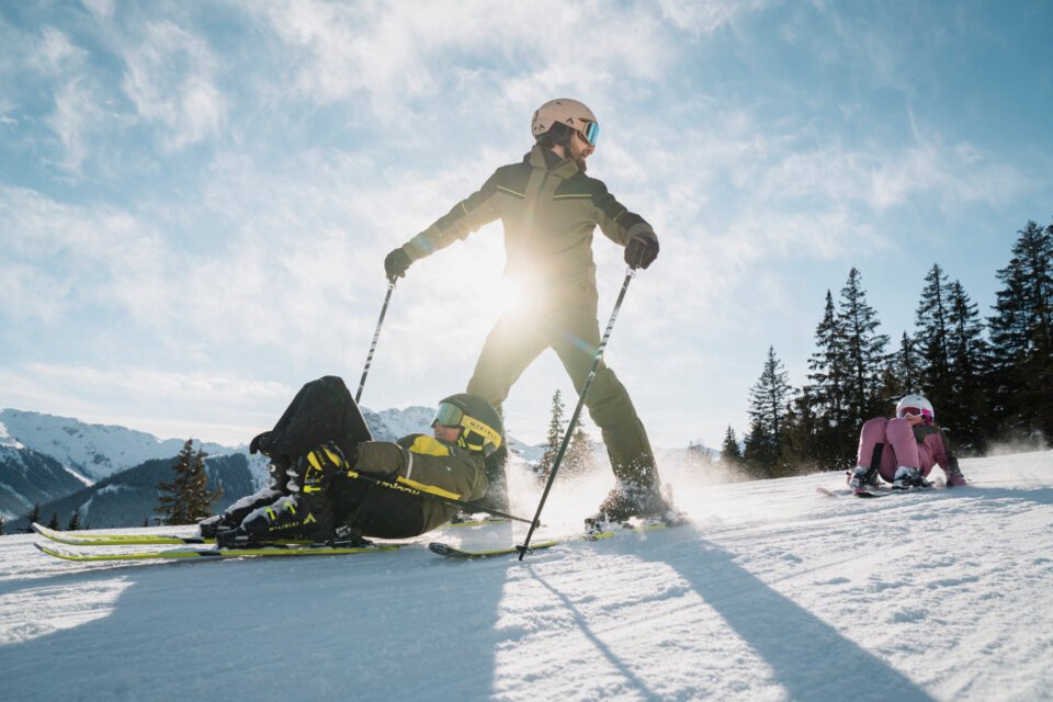 Skier falling and being skied over, with child sitting in background. | © INTERSPORT International Corporation GmbH
