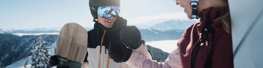 Twee snowboarders schudden elkaar de hand in de sneeuw. | © INTERSPORT International Corporation GmbH