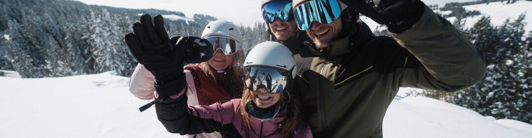 © INTERSPORT International Corporation GmbH Groep van vier skiërs zwaait in de bergen. | © INTERSPORT International Corporation GmbH