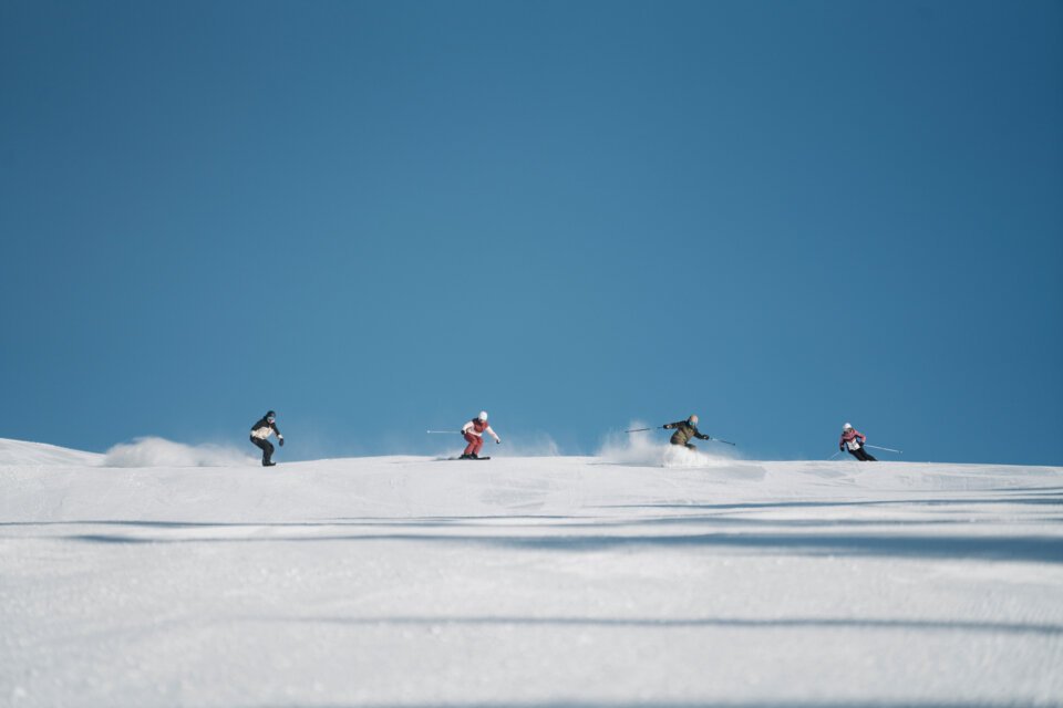 © INTERSPORT International Corporation GmbH Groupe de skieurs sur une piste enneigée sous un ciel bleu. | © INTERSPORT International Corporation GmbH