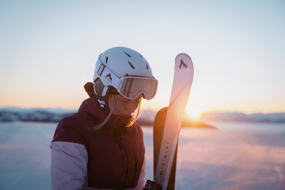 Skifahrerin mit Helm und Skiern im Sonnenuntergang | © INTERSPORT International Corporation GmbH