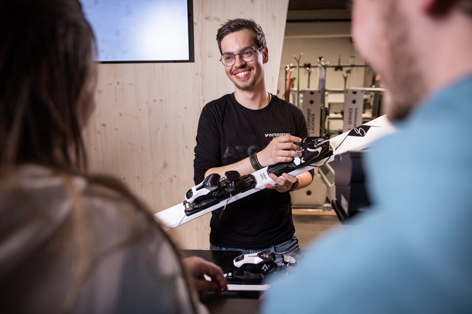 A smiling man wearing glasses holds a ski. | © IIC - INTERSPORT International Corporation GmbH