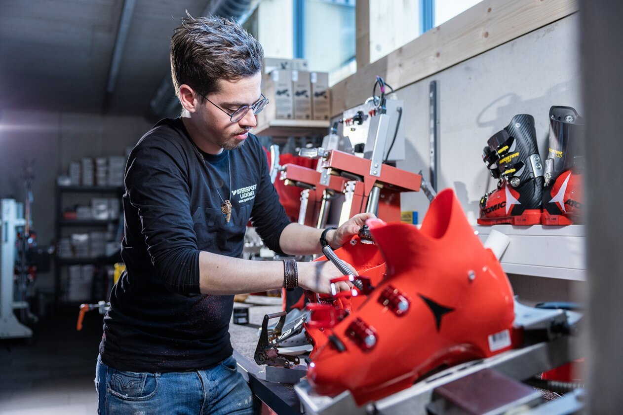Homme travaillant sur une chaussure de ski rouge | © IIC - INTERSPORT International Corporation GmbH