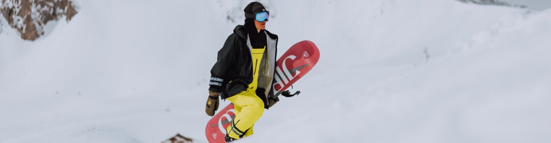 Snowboarder carrying snowboard in snowy mountain landscape. | © Oliver Godbold photography / ROSSIGNOL