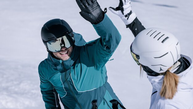 Two skiers giving a high-five in the snow. | © IIC - INTERSPORT International Corporation GmbH