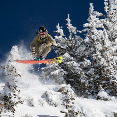 Skieur sautant au-dessus d'arbres enneigés. | © Salomon