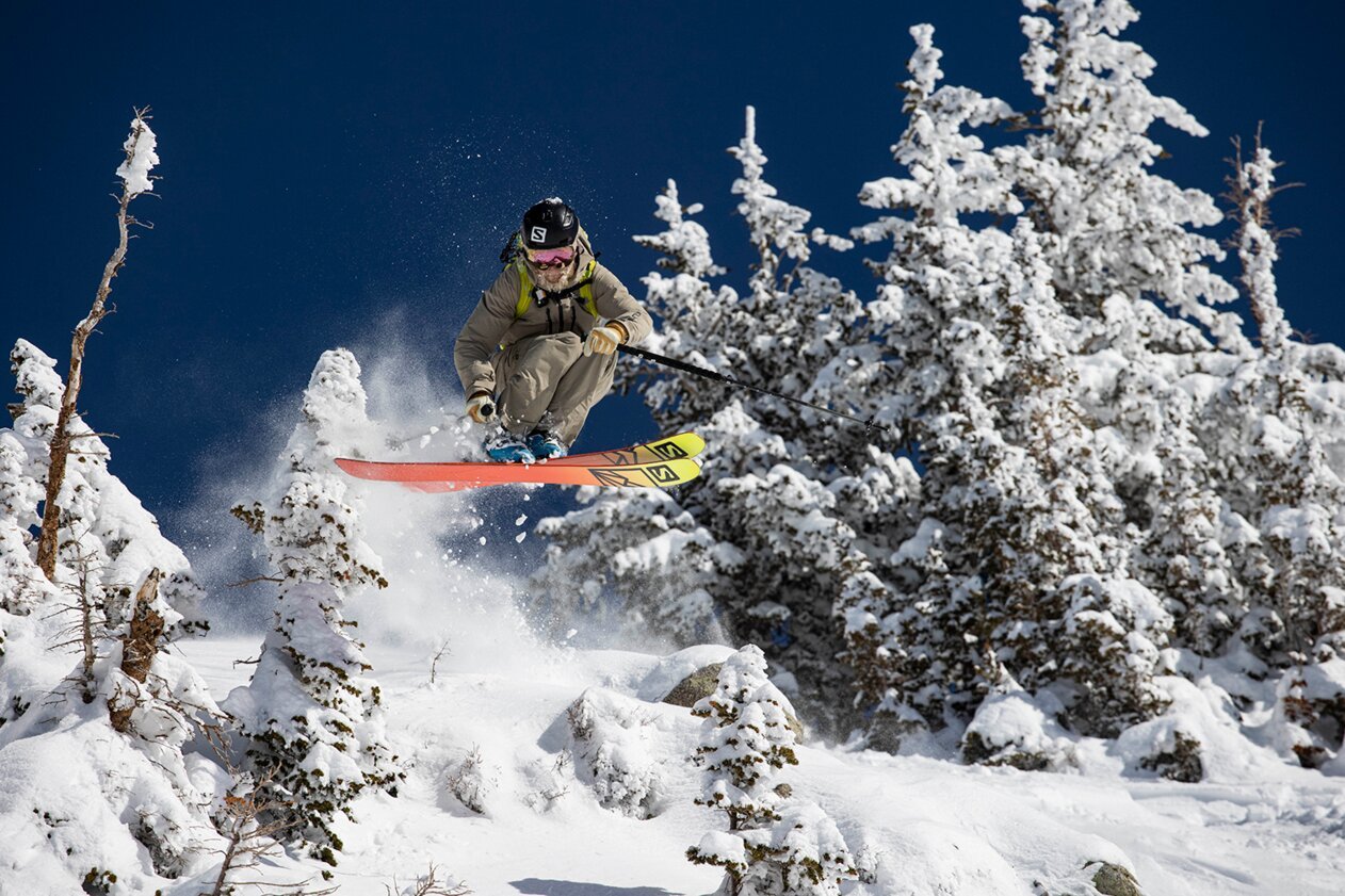 Skier jumping over snow-covered trees. | © Salomon