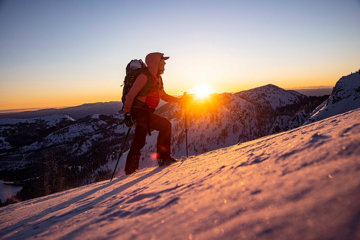 Personne faisant de la randonnée sur une montagne enneigée au lever du soleil. | © Salomon