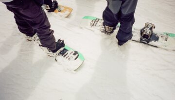 Two people with snowboards in the snow. | © Salomon