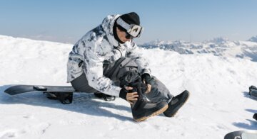 Snowboarder sitting and adjusting boot | © Salomon