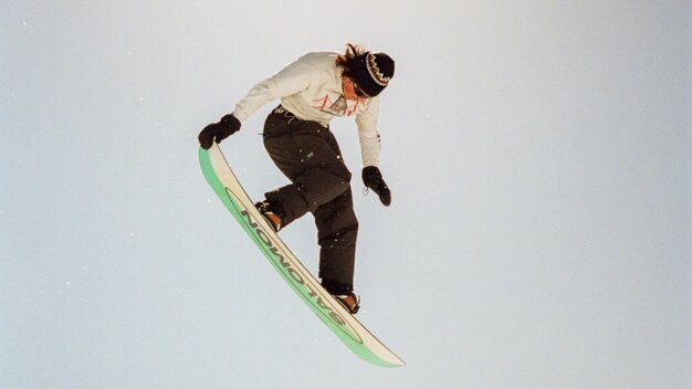 Snowboarder in mid-air with mountain backdrop. | © Salomon