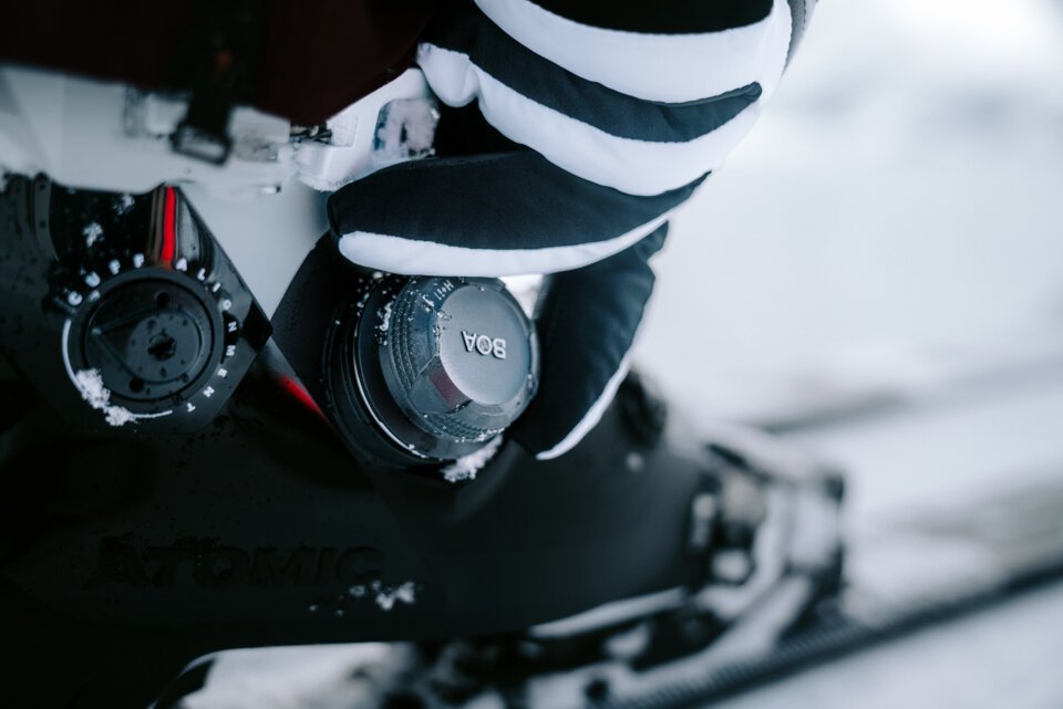 INTERSPORT Rent Atomic Skiing Boa Skiboot Close-up of a ski boot with BOA closure, being adjusted by a gloved hand.