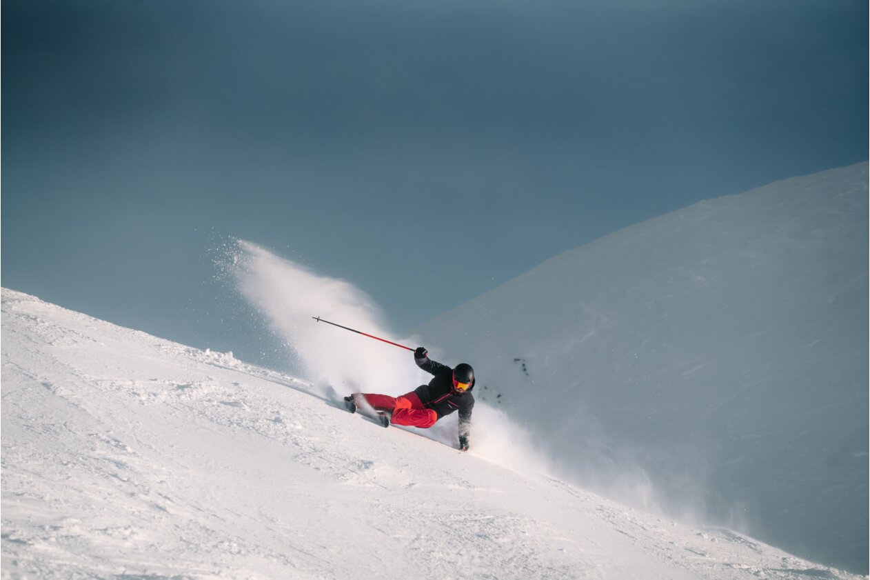Skifahrer beim Abfahren eines verschneiten Hanges.