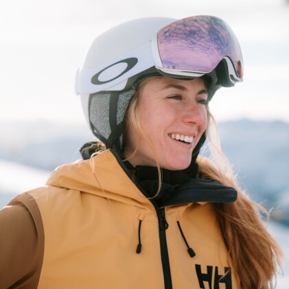 Femme souriante portant un casque et des lunettes de ski.