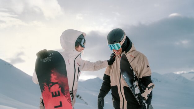 Deux snowboarders debout dans un paysage enneigé avec des snowboards.