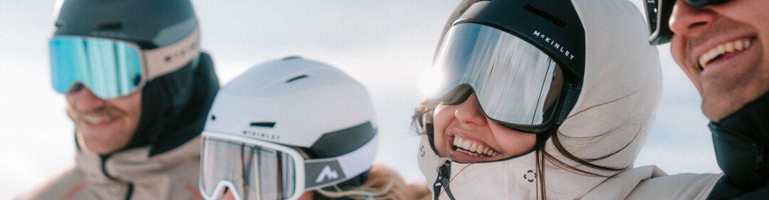 Groupe de quatre personnes souriantes avec des casques et des lunettes de ski.