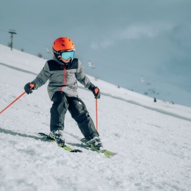 Kind fährt Ski auf einer verschneiten Piste.