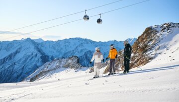 Trois skieurs sur une piste avec vue sur la montagne.