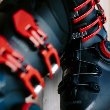 Close-up van zwarte skischoenen met rode gespen en een BOA-systeem.