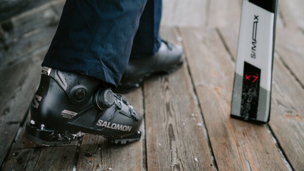 Chaussure de ski Salomon avec un ski en arrière-plan.