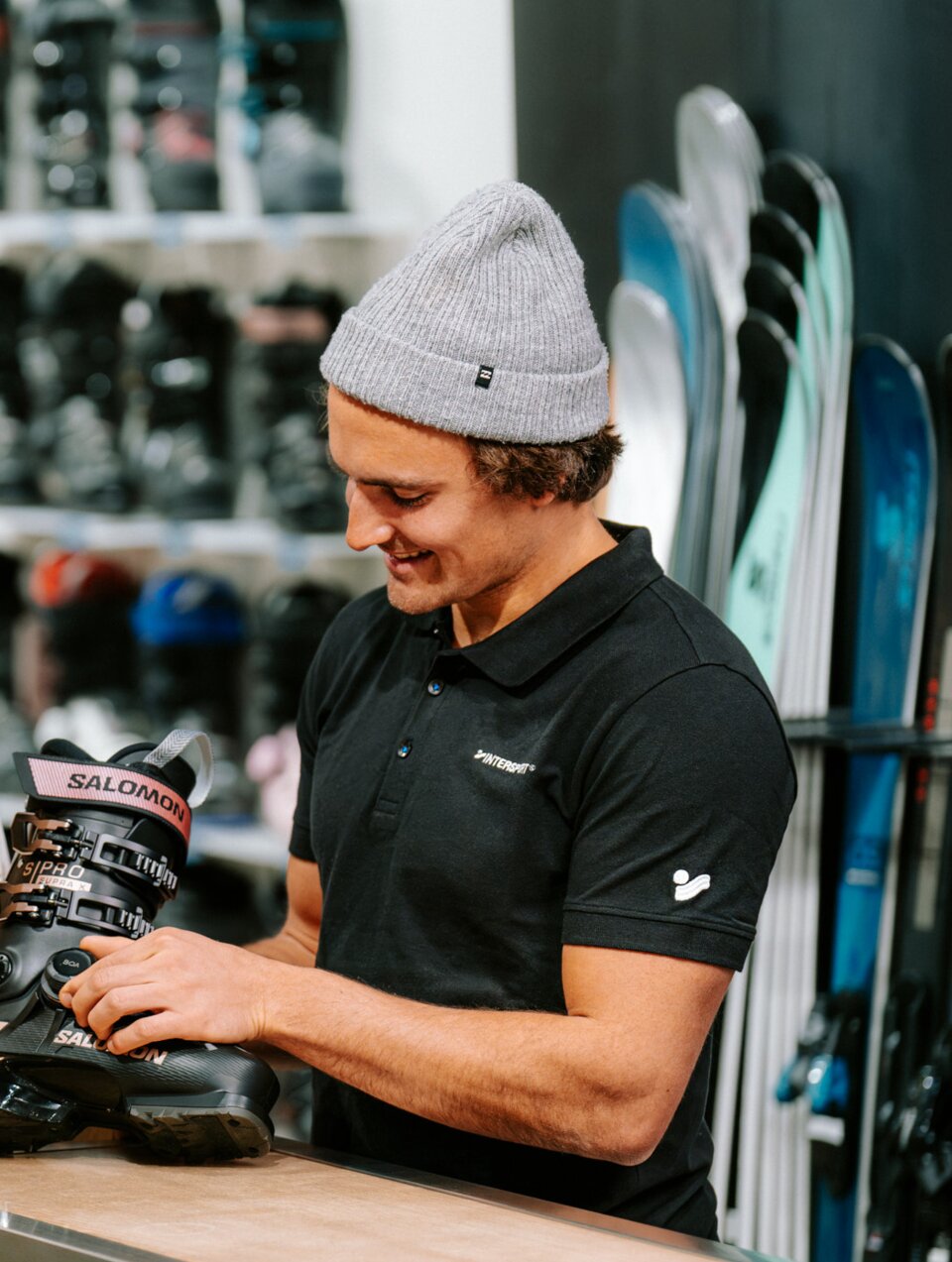 Une femme regarde avec approbation un vendeur qui lui montre des chaussures de ski.