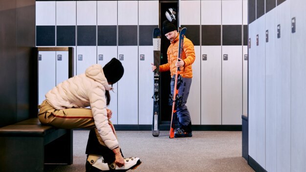 Deux personnes se préparent à skier dans un local à skis. | © ARMIN WALCHER