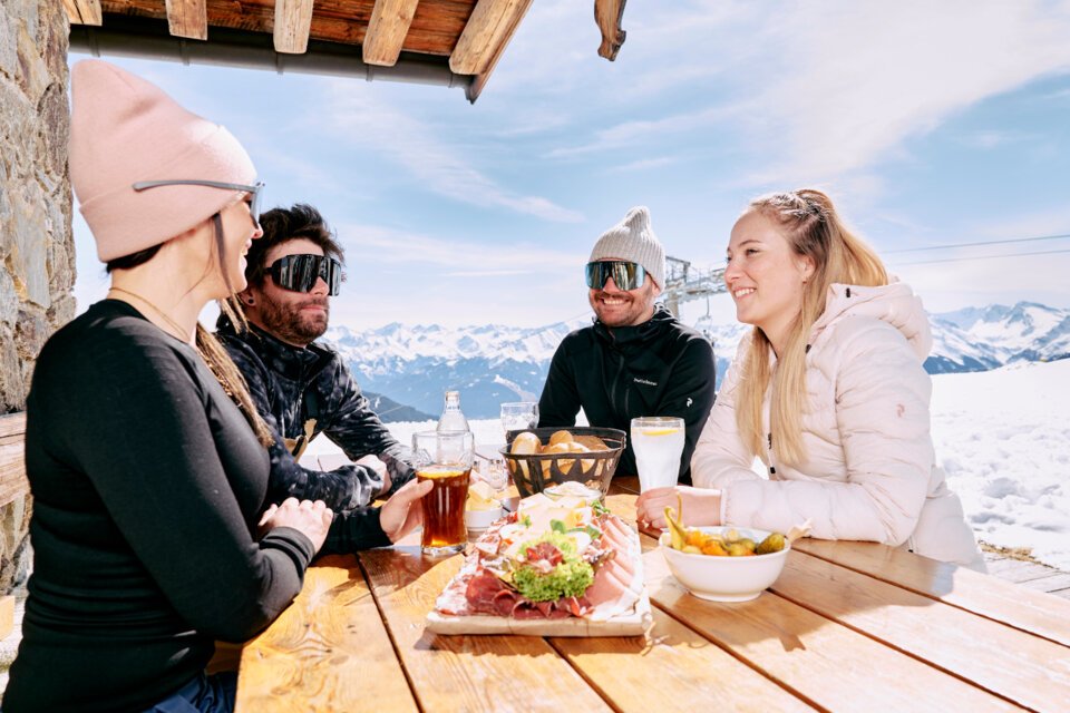 © ARMIN WALCHER Gruppe von Freunden isst auf einer Skihütte. | © ARMIN WALCHER
