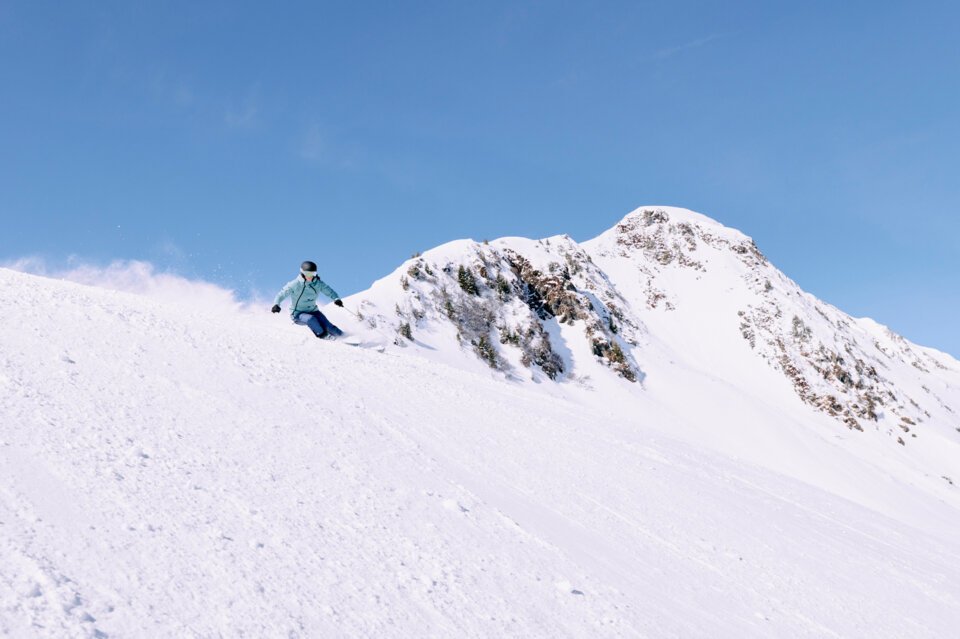 © ARMIN WALCHER Skifahrerin auf schneebedecktem Hang unter blauem Himmel. | © ARMIN WALCHER