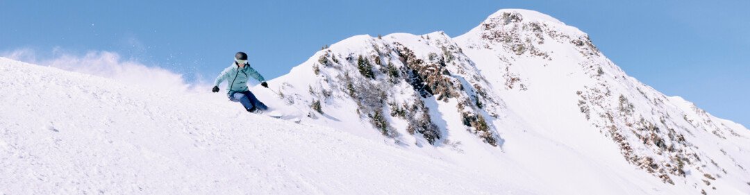 Skiër op besneeuwde helling onder blauwe lucht. | © ARMIN WALCHER