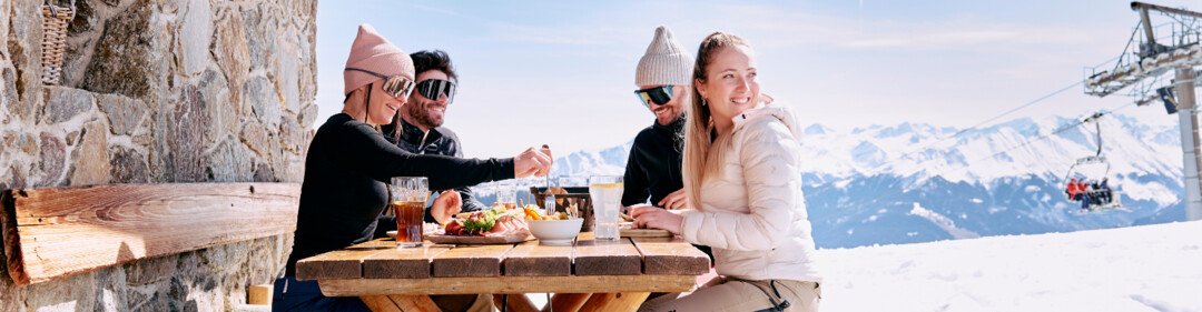Groep skiërs eet aan een buitentafel. | © ARMIN WALCHER