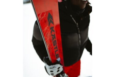 Person holding red KÄSTLE skis.