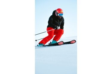 Skier in red pants and black jacket skiing